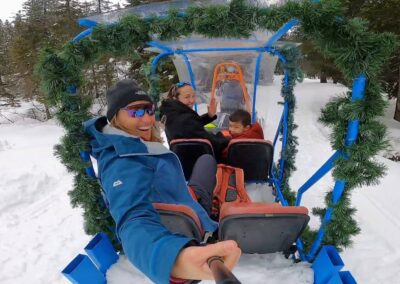 Family enjoying a horse-drawn sleigh ride through a snowy forest in Madonna di Campiglio, Dolomiti di Brenta