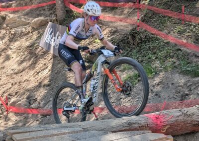 Mountain biker crossing a log obstacle during a World Cup mountain bike race in Val di Sole
