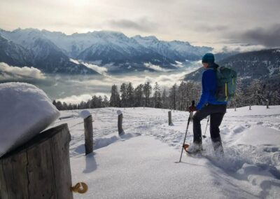Snowshoe hiking with panoramic views of the snow-covered mountains and valley in Val di Sole