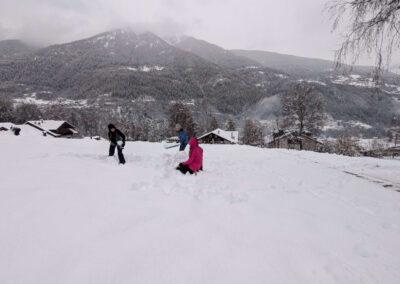 Family playing in deep snow in front of Villa Meledrio in Dimaro, Val di Sole, with mountain views