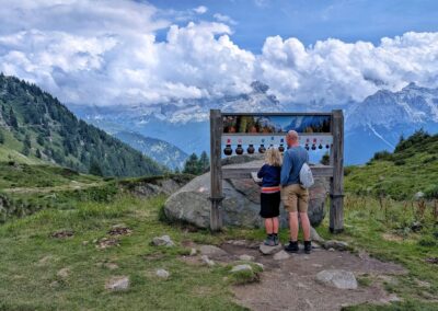 Two hikers exploring a music mountain trail with panoramic views of the Brenta Dolomites