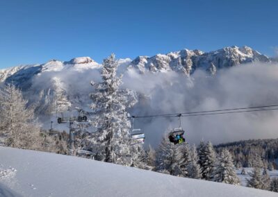 SkiArea Campiglio Dolomiti di Brenta chairlift above snow-covered forests with panoramic views in Val di Sole, Italy