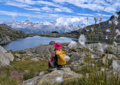 Hiker relaxing beside an alpine lake with panoramic views of the Brenta Dolomites
