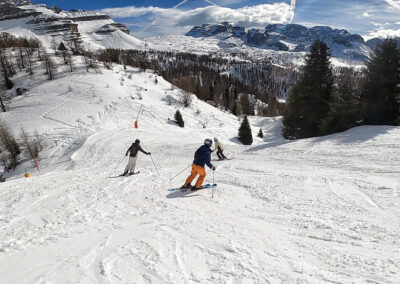 Skiers descending a snowy mountain slope with panoramic views of the Brenta Dolomites in Folgarida Marilleva, Italy