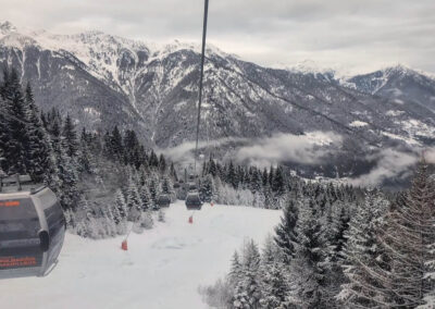 Folgarida Marilleva ski gondola above snow-covered forests and mountains in Val di Sole, Italy