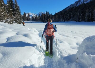 Snowshoe hiking through a snowy alpine valley surrounded by forests and mountains in Val di Rabbi, Trentino, Italy