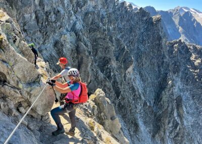 Via ferrata climbers crossing a steep rocky mountain ridge with safety cables in Dolomiti di Brenta, Italian Alps